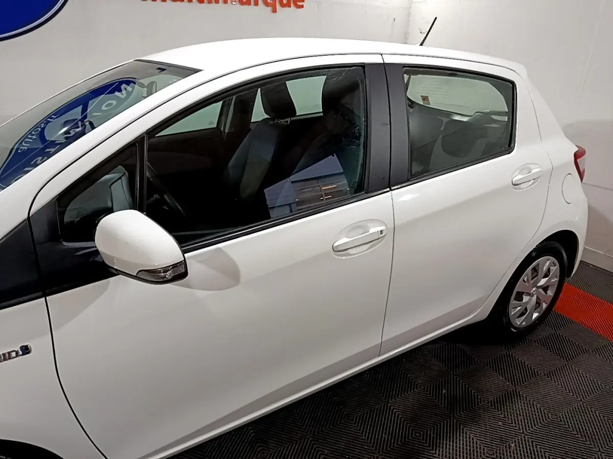 Vue latérale droite d'une Toyota Yaris blanche 2019 hybride avec rétroviseurs intégrant clignotants.