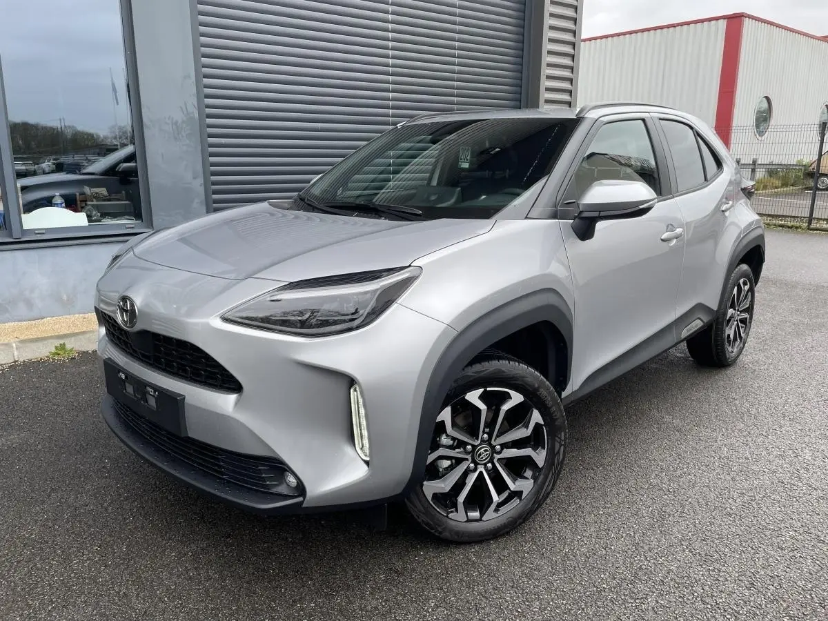 Toyota Yaris Cross gris clair vue 3/4 avant droit, avec phares LED et jantes alliage noires et argentées.