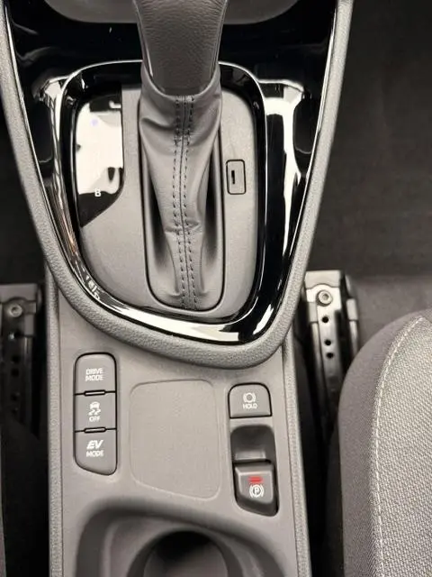 Gros plan sur la console centrale noire de la Toyota Yaris Cross 1.5 Hybrid, avec levier de vitesse automatique et boutons de contrôle.