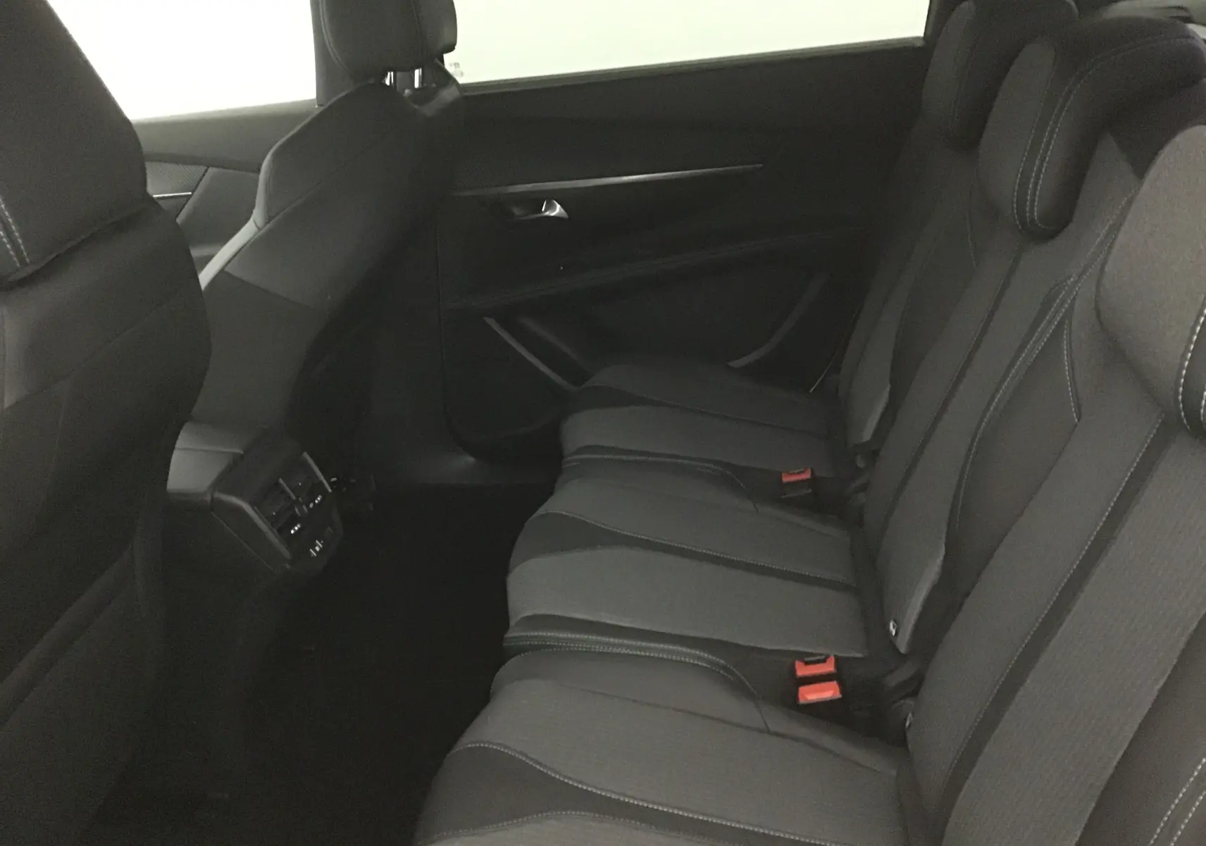 Vue latérale droite de l'habitacle arrière du Peugeot 5008 2024, sièges en tissu noir et gris avec surpiqûres contrastées.
