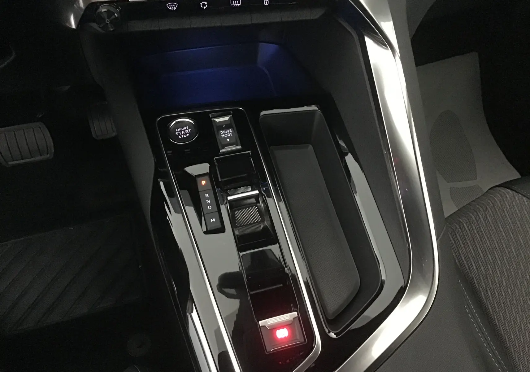 Vue rapprochée de la console centrale noire brillante du Peugeot 5008 2024 avec levier de vitesses automatique et bouton start-stop.