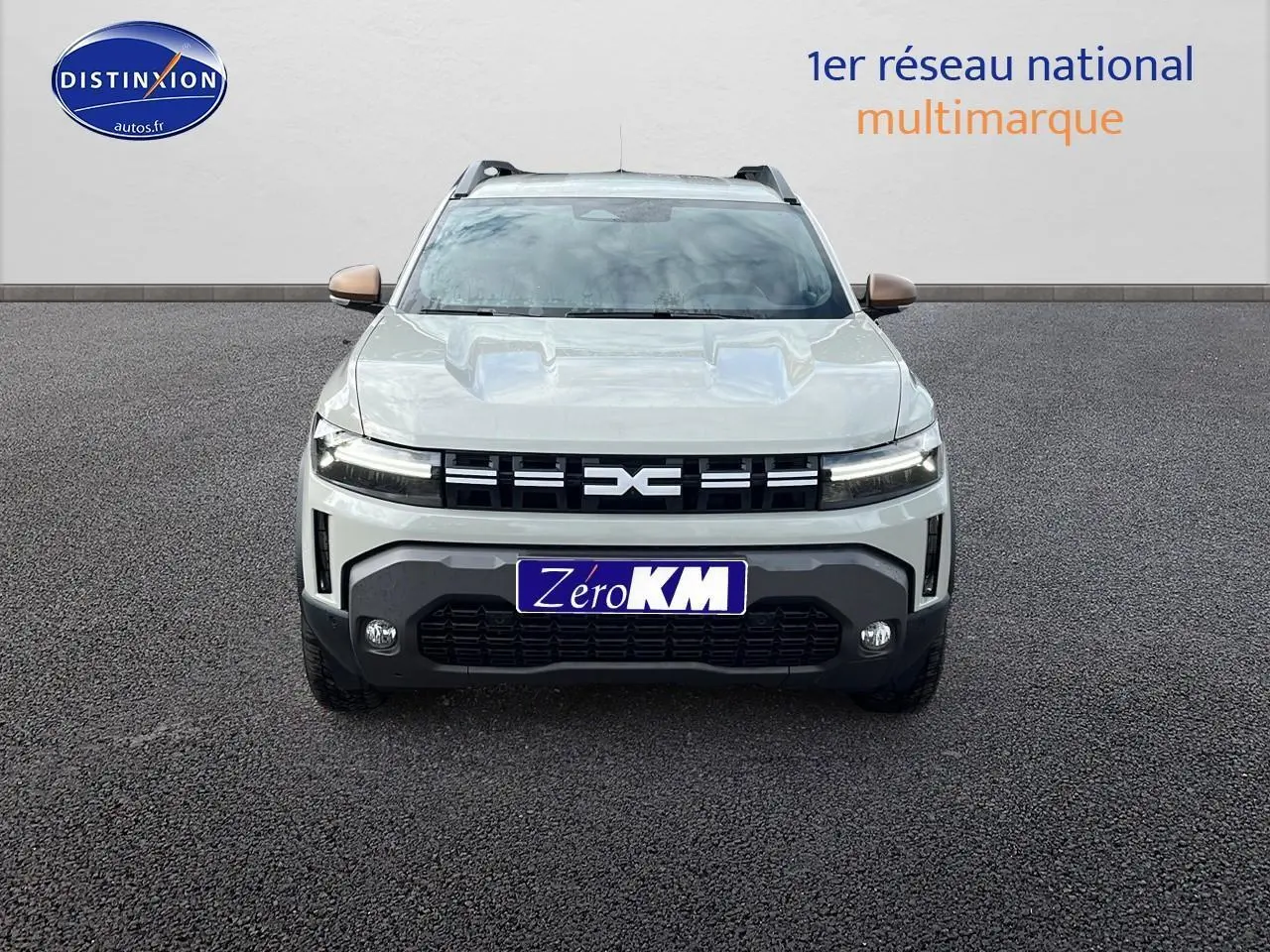 Vue frontale d'un Dacia Duster 2025 couleur Sandstone avec calandre noire et phares LED allumés.