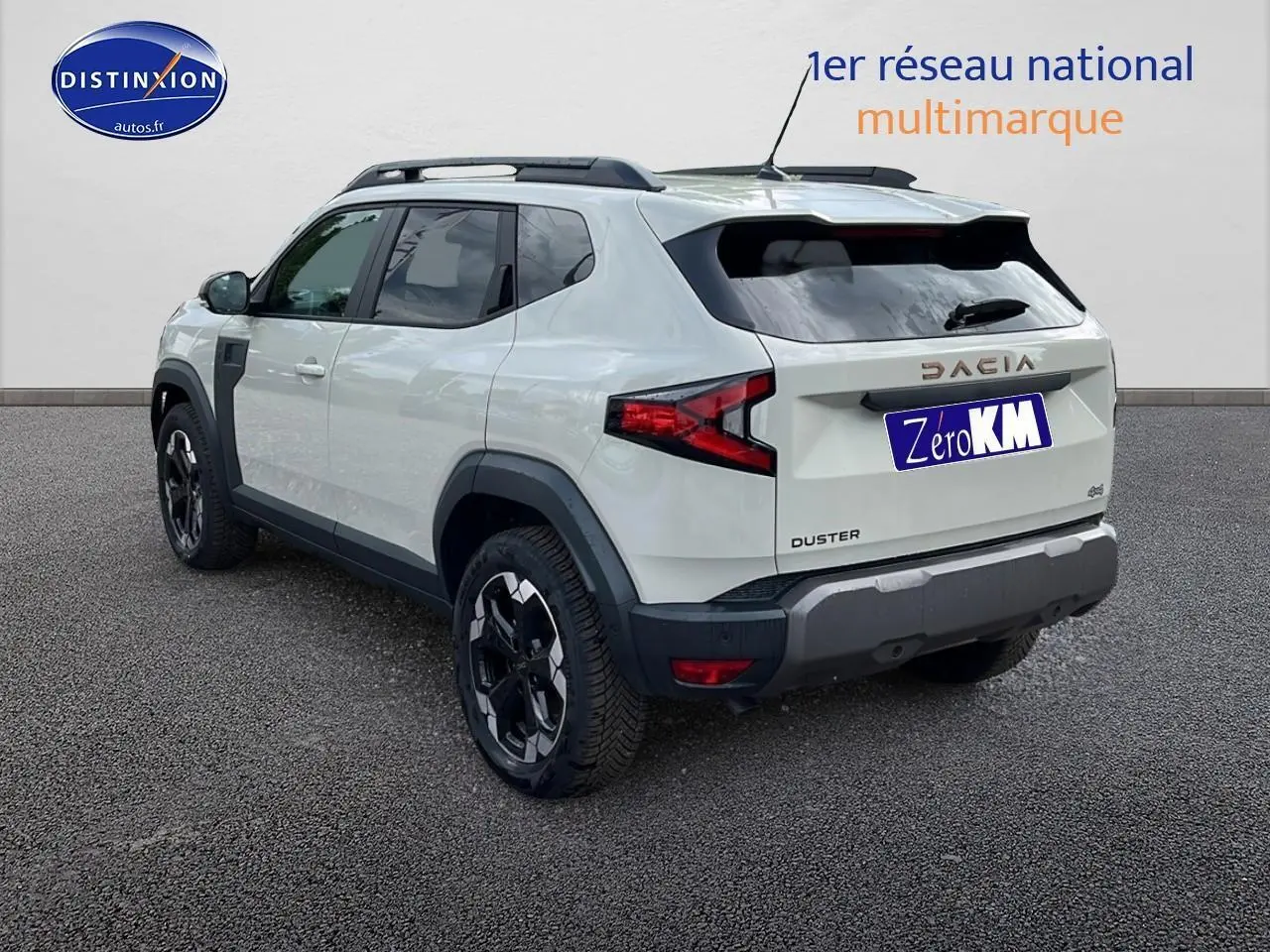 Vue 3/4 arrière droite du Dacia Duster 2025 couleur Sandstone avec barres de toit et jantes noires distinctives.