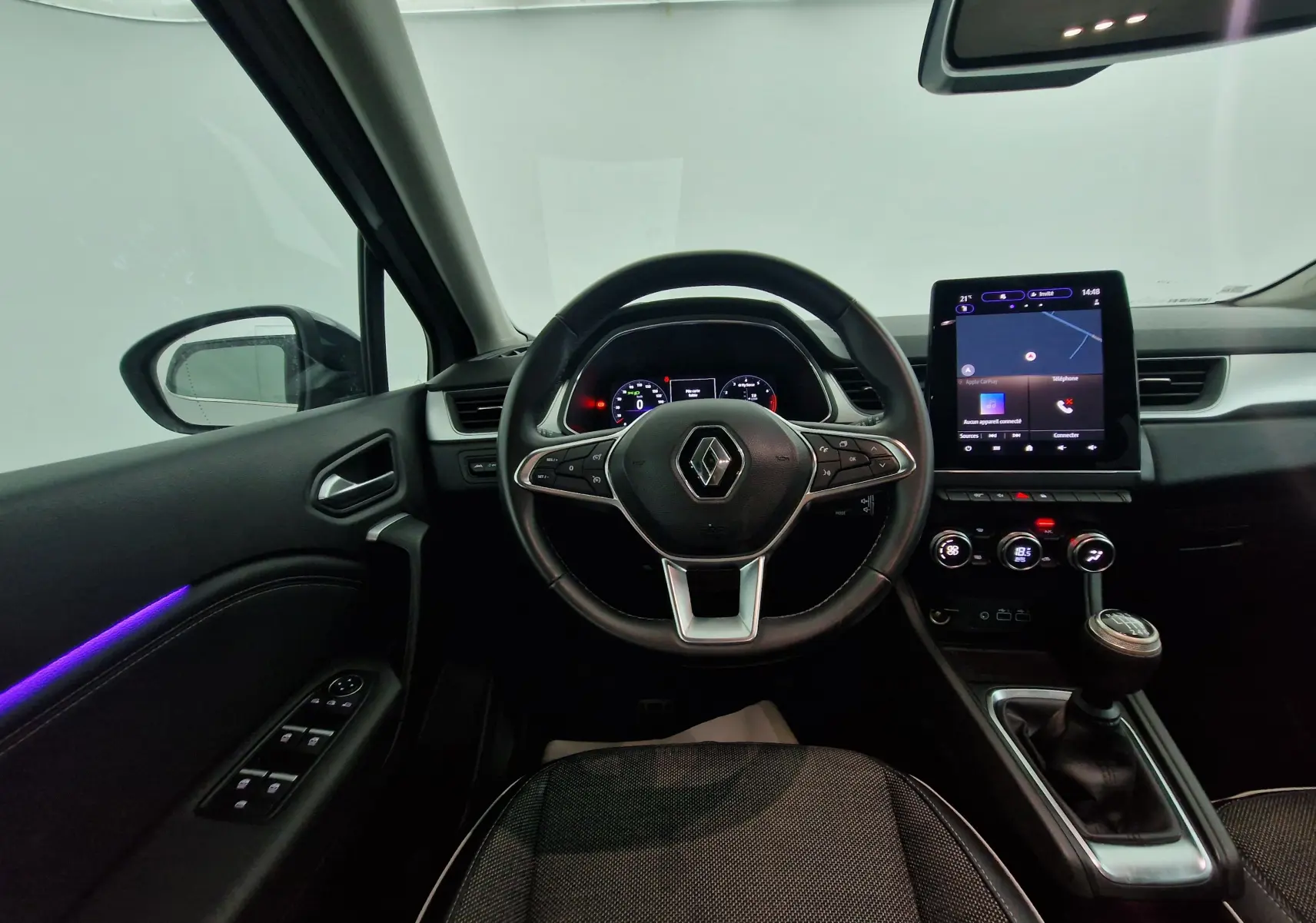 Vue intérieure du poste de conduite du Renault Captur 2024 avec volant multifonction, écran tactile vertical et levier de vitesses manuel.