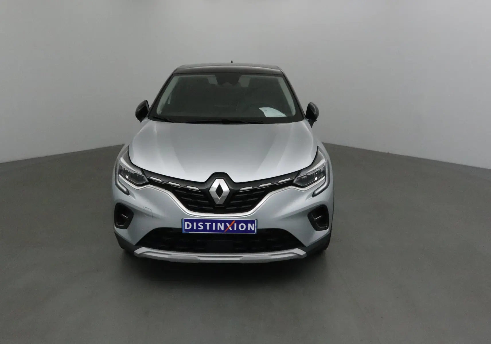 Vue avant d'un Renault Captur 2024 gris Highland avec toit noir et calandre marquée Renault.