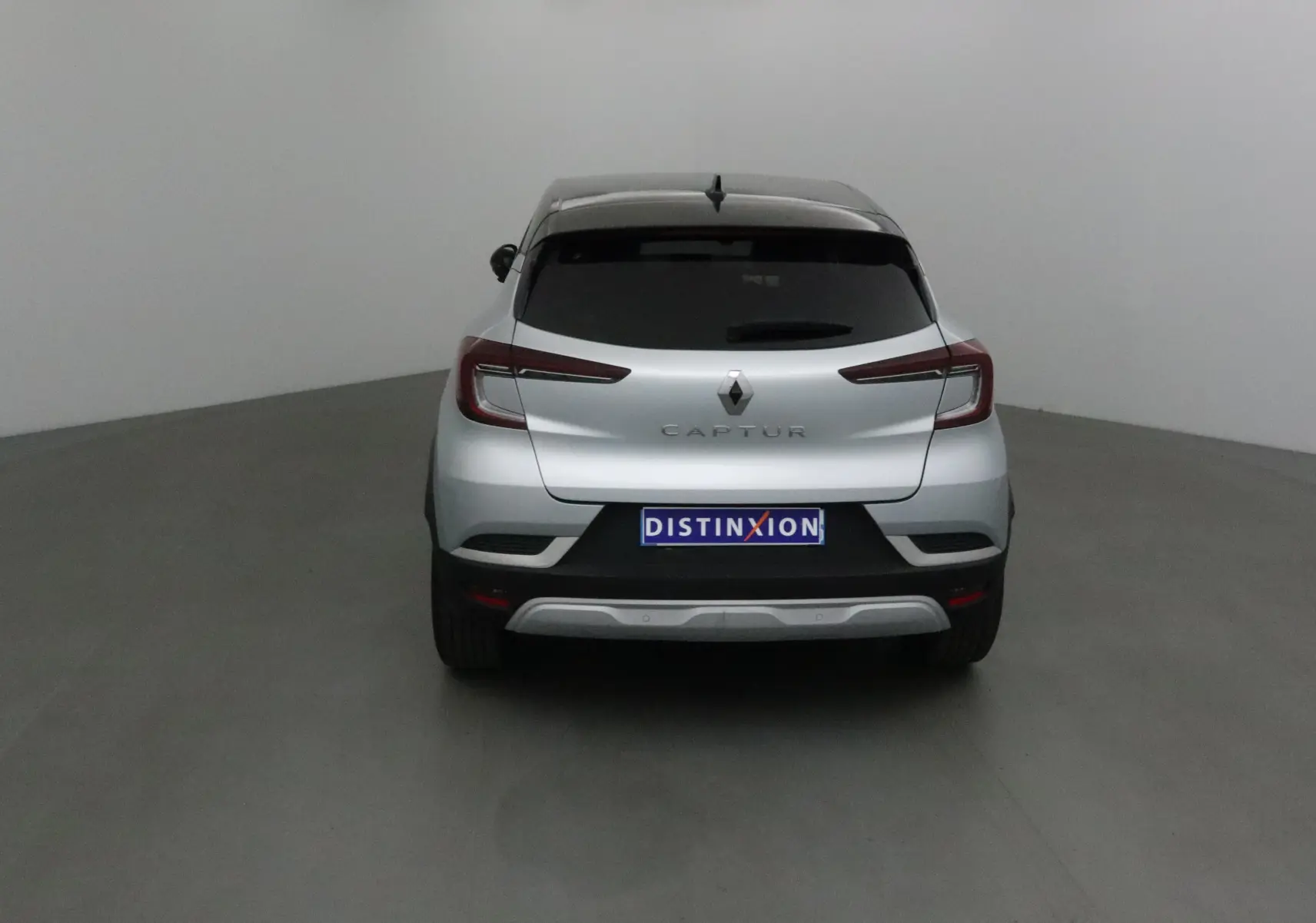 Vue arrière d'un Renault Captur 2024 gris Highland avec toit noir et feux arrière LED distinctifs.