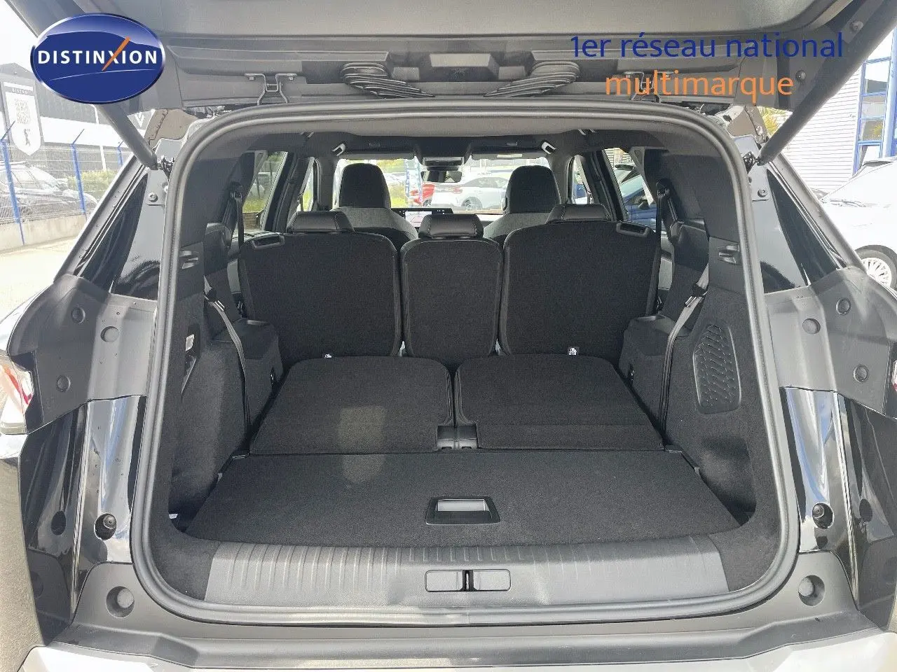 Coffre ouvert du Peugeot 5008 HYBRID noir perle métal, montrant les sièges arrière rabattus et l'espace de chargement.