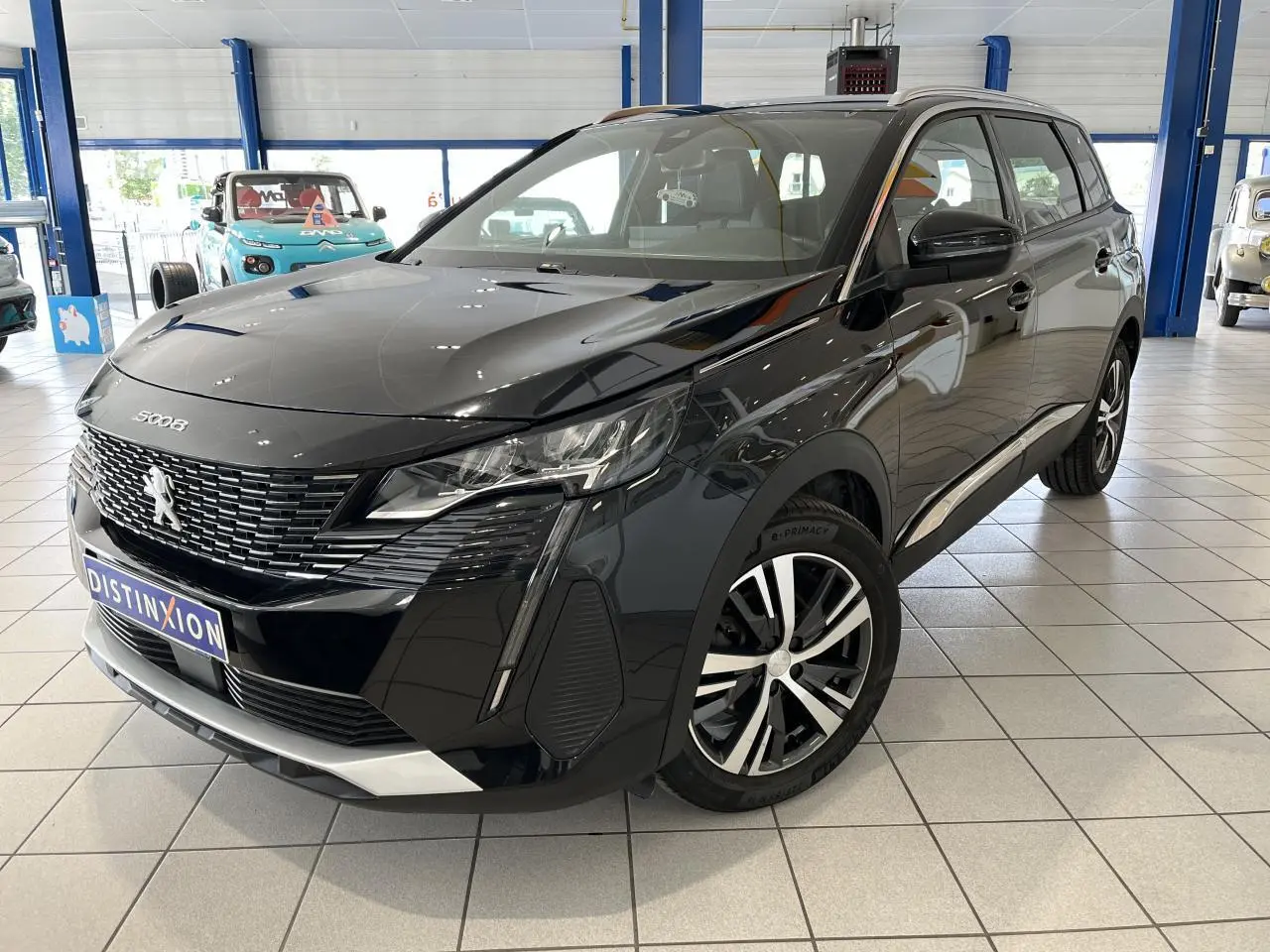 Peugeot 5008 noir métallisé vue 3/4 avant droit en intérieur avec jantes alliage bi-ton et calandre chromée.