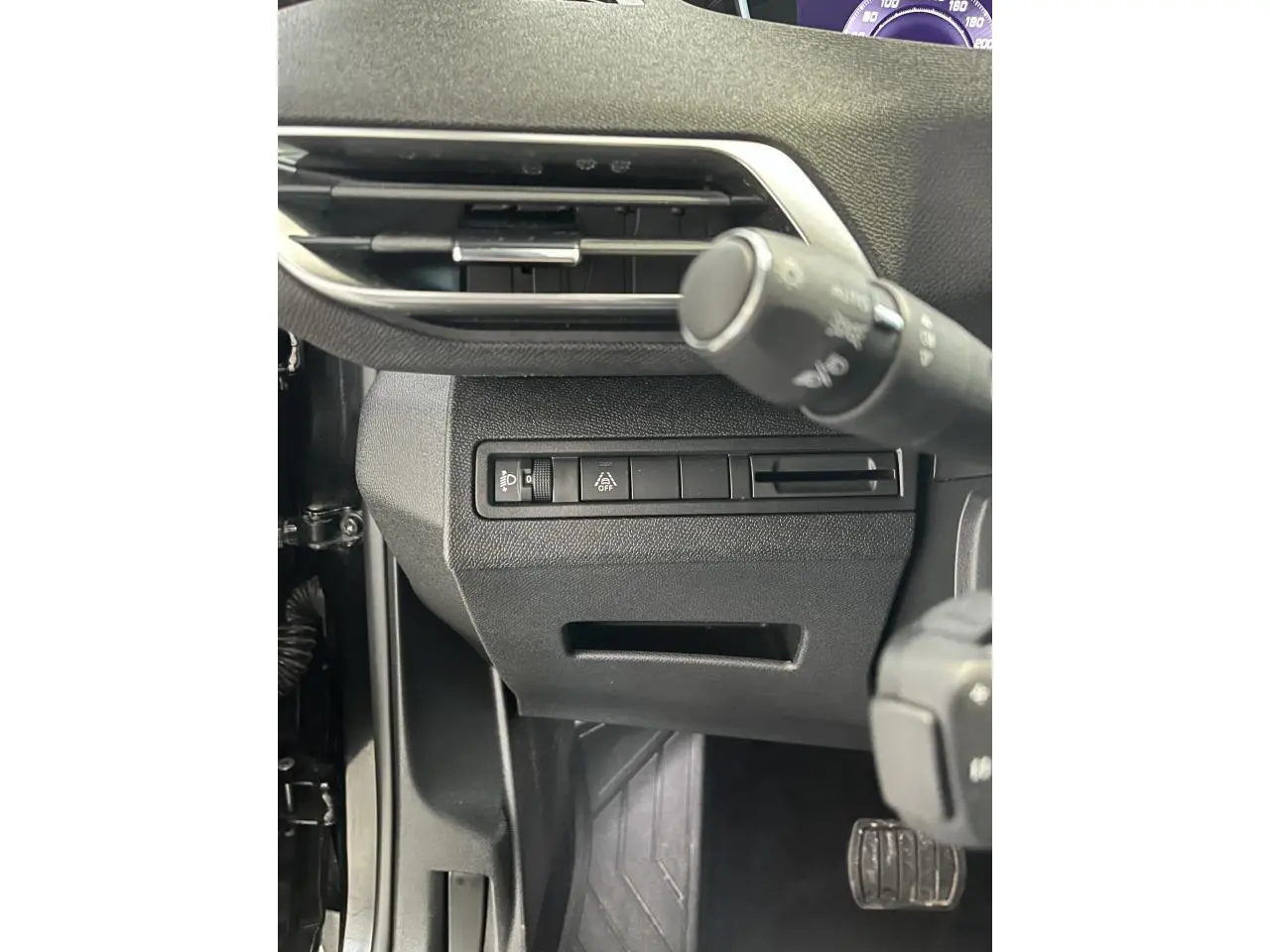 Détail des commandes sous le volant côté gauche du Peugeot 5008 noir métallisé 2024, avec bouton d'éclairage et aide à la conduite.