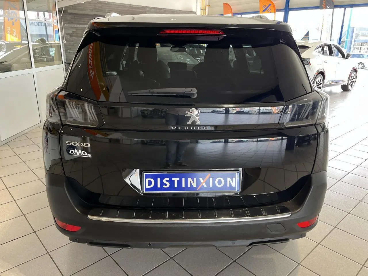 Vue arrière d'un Peugeot 5008 noir métallisé exposé en showroom avec feux arrière LED 3D et logo central chromé.