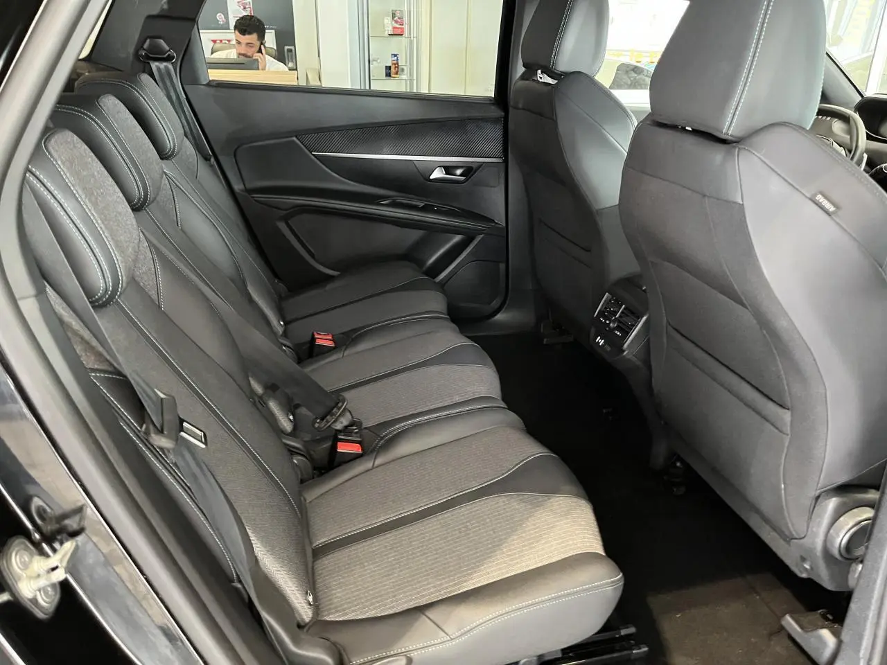 Vue intérieure côté gauche des sièges arrière en tissu et cuir du Peugeot 5008 noir métallisé 2024 avec finitions carbone.
