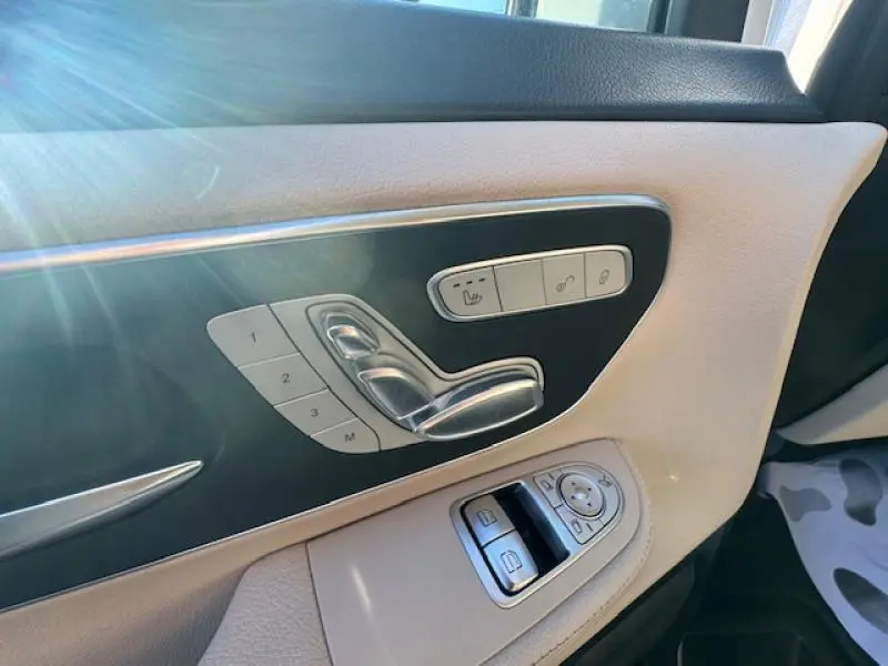 Détail côté gauche de la porte avant en cuir beige avec commandes sièges et vitres du Mercedes Classe V blanc cristal de roche