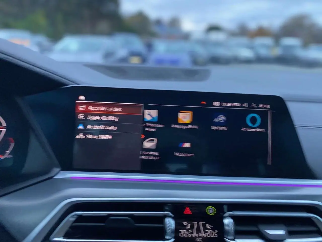 Écran central tactile du tableau de bord du BMW X5 blanc 2022, affichant le menu multimédia avec éclairage d'ambiance violet.