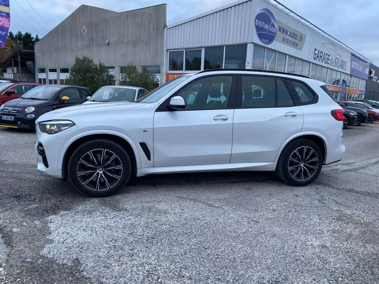 BMW X5 xDrive 30d blanc en vue profil côté gauche, avec jantes M Sport noires et détails sportifs visibles.