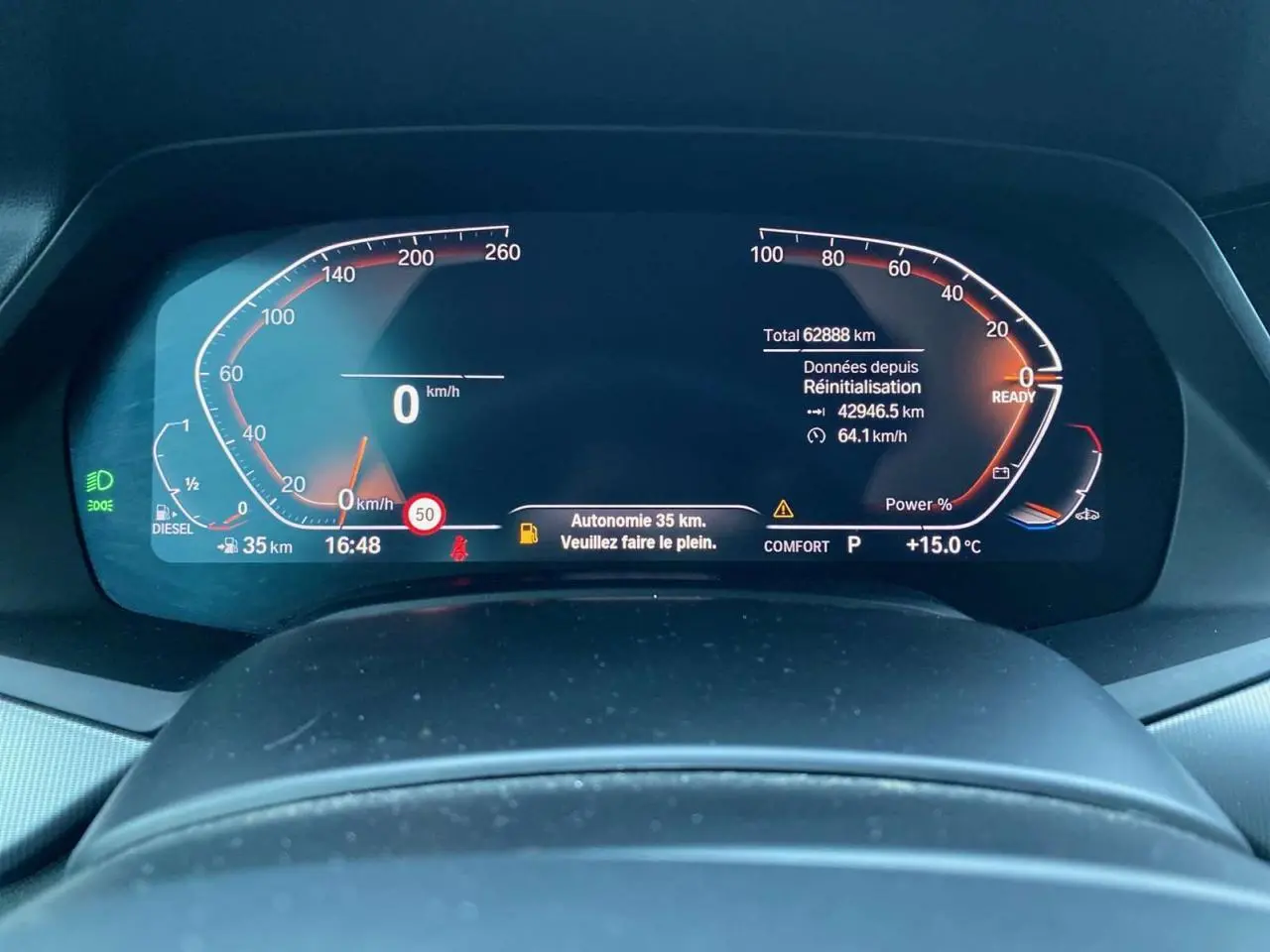 Tableau de bord numérique du BMW X5 blanc 2022 xDrive 30d, affichant vitesse, autonomie et alertes à 16h48.