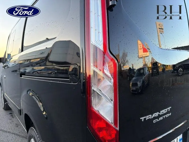 Vue rapprochée arrière droite du Ford Transit Custom noir Agate métallisé avec feu arrière vertical et logo visible.