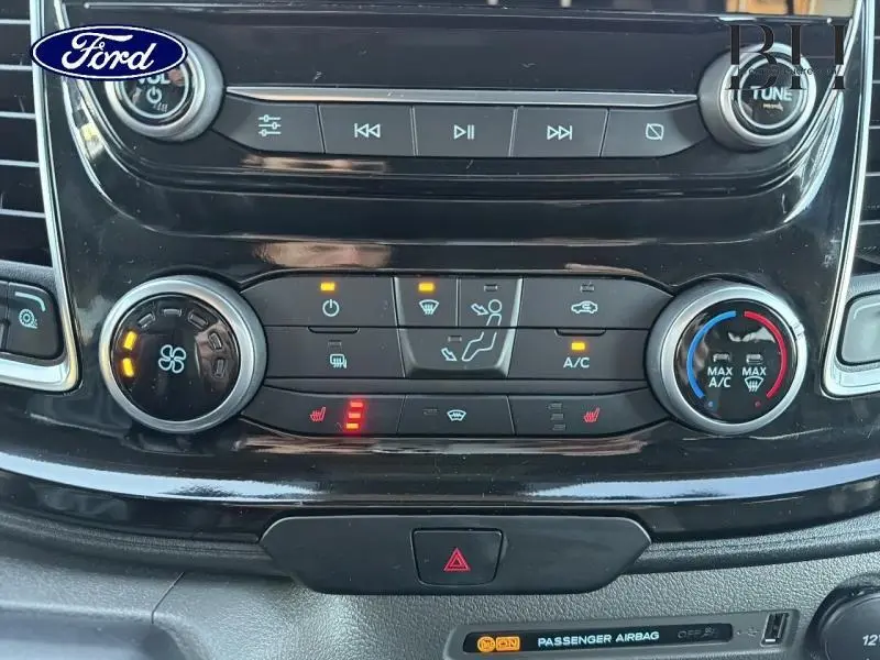 Gros plan sur la console centrale noire du Ford Transit Custom 2023, avec commandes climatisation et audio éclairées.