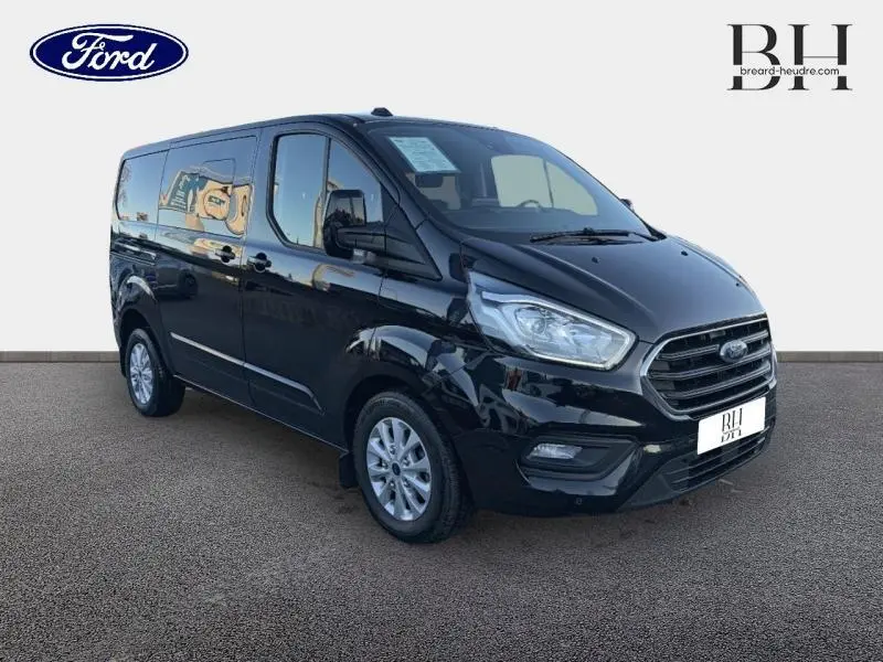 Ford Transit Custom Fourgon noir Agate métallisé vu en 3/4 avant droit avec calandre chromée et jantes alu 16 pouces.