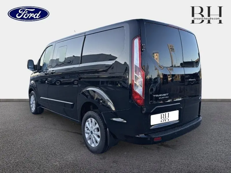 Vue 3/4 arrière droite d'un Ford Transit Custom noir Agate métallisé avec portes arrière battantes et jantes alu 16 pouces.