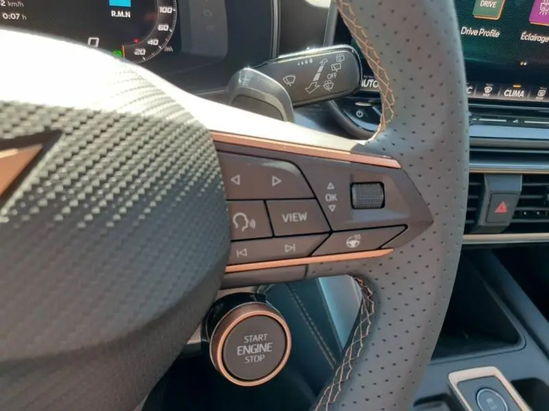 Gros plan sur le volant sport perforé et les commandes multifonctions du CUPRA Formentor bleu, avec bouton démarrage visible.