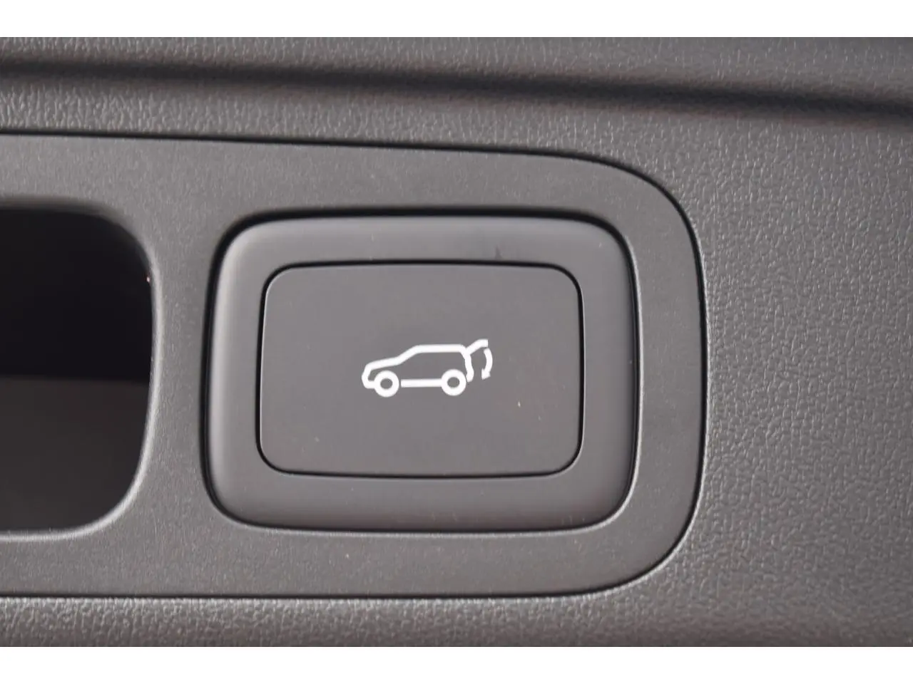 Bouton intérieur noir avec symbole blanc d'ouverture du hayon sur MG Motor EHS hybride.