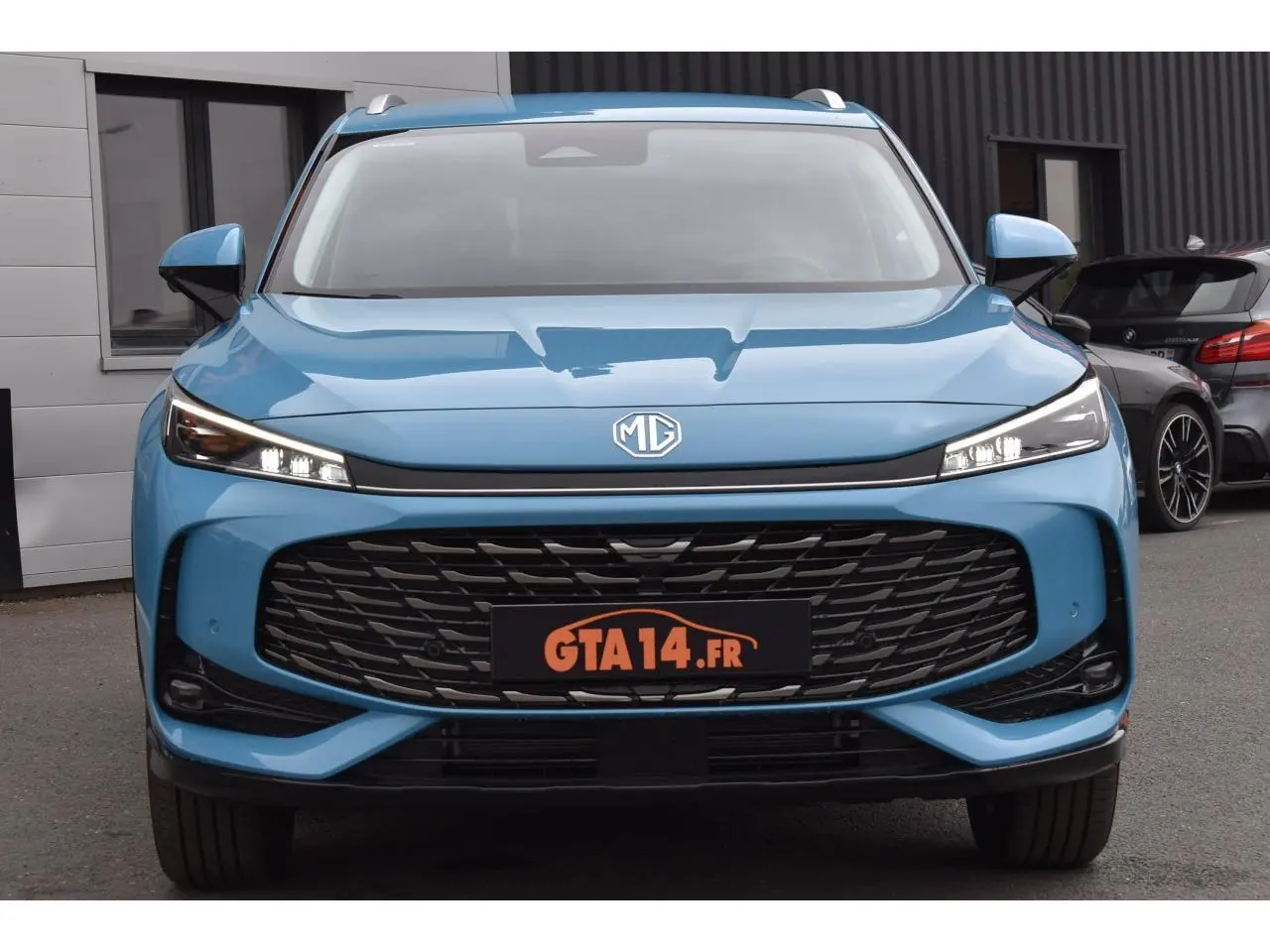 Vue frontale d’un MG MOTOR EHS 1.5 Hybrid+ 224 ch Luxury bleu avec calandre large et phares LED fins.