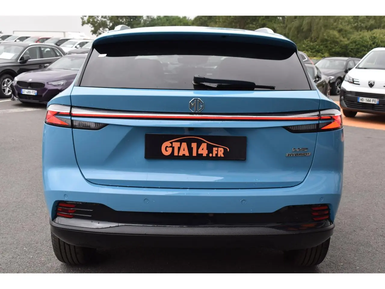 Vue arrière d'un MG MOTOR EHS bleu avec feux LED reliés par une bande lumineuse rouge et logo central.