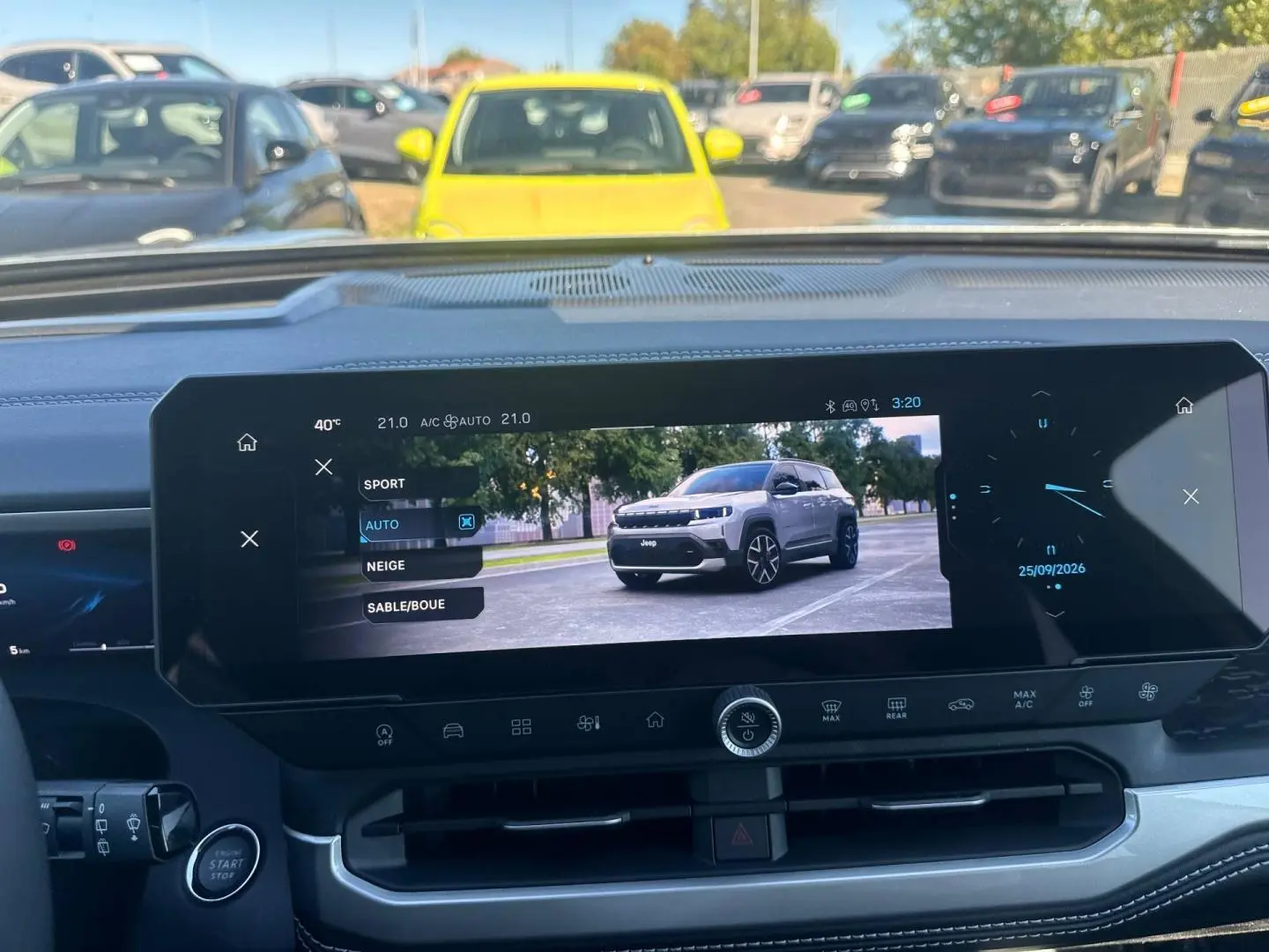 Vue intérieure du tableau de bord du Jeep Compass 2026 avec écran tactile affichant un mode de conduite et une image du véhicule gris.