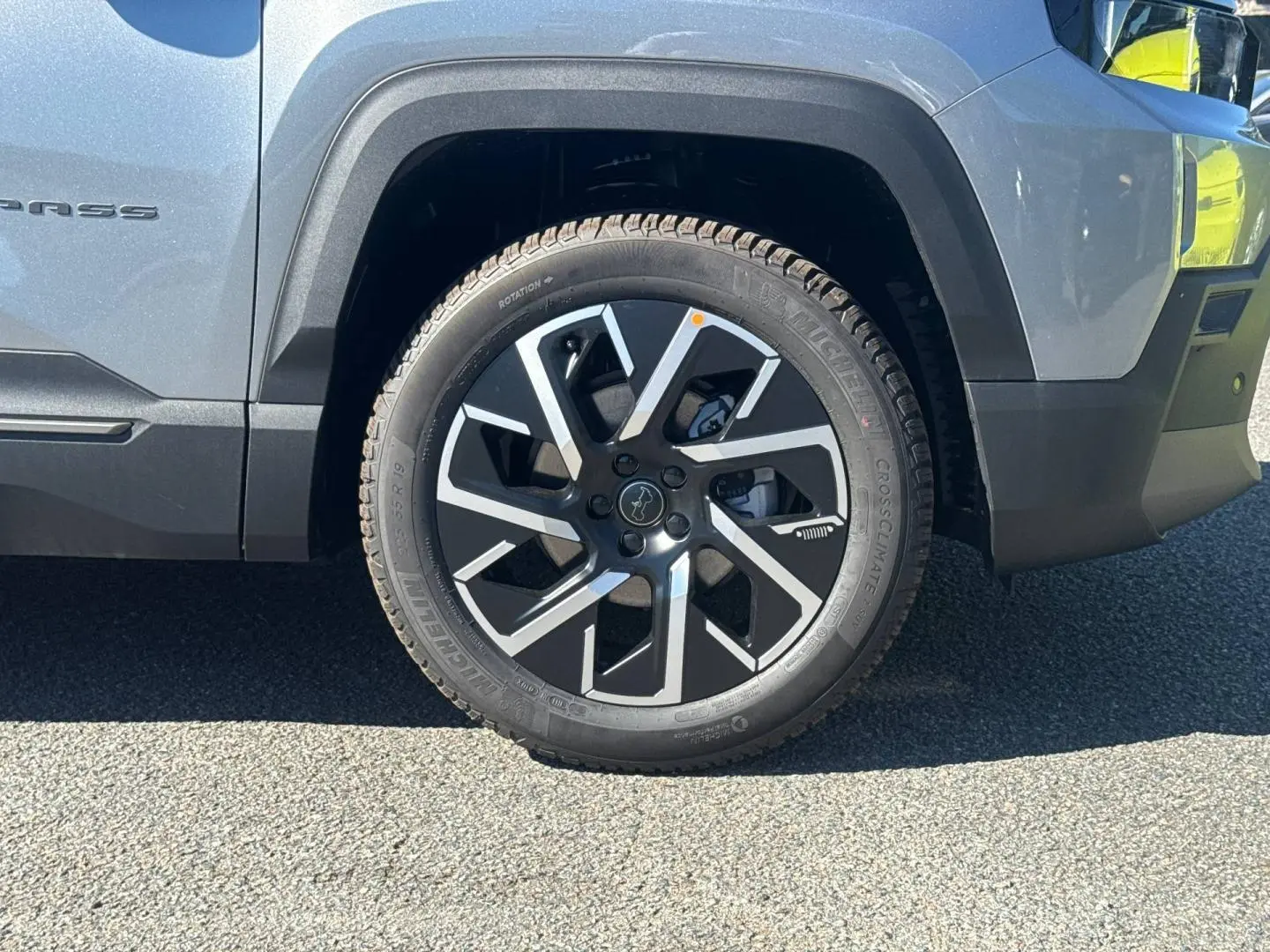 Gros plan sur la roue avant droite du Jeep Compass Yosemite gris avec jante alu noire et grise, partie latérale visible.