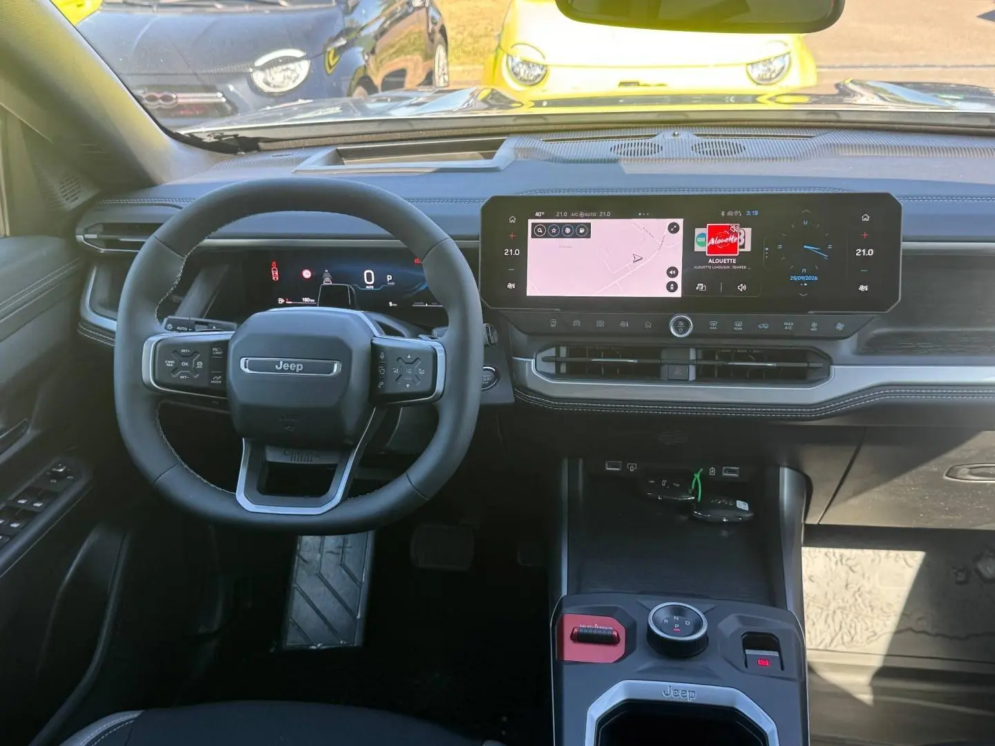 Vue intérieure frontale du tableau de bord du Jeep Compass 2026, avec écran tactile large et volant multifonctions noir.