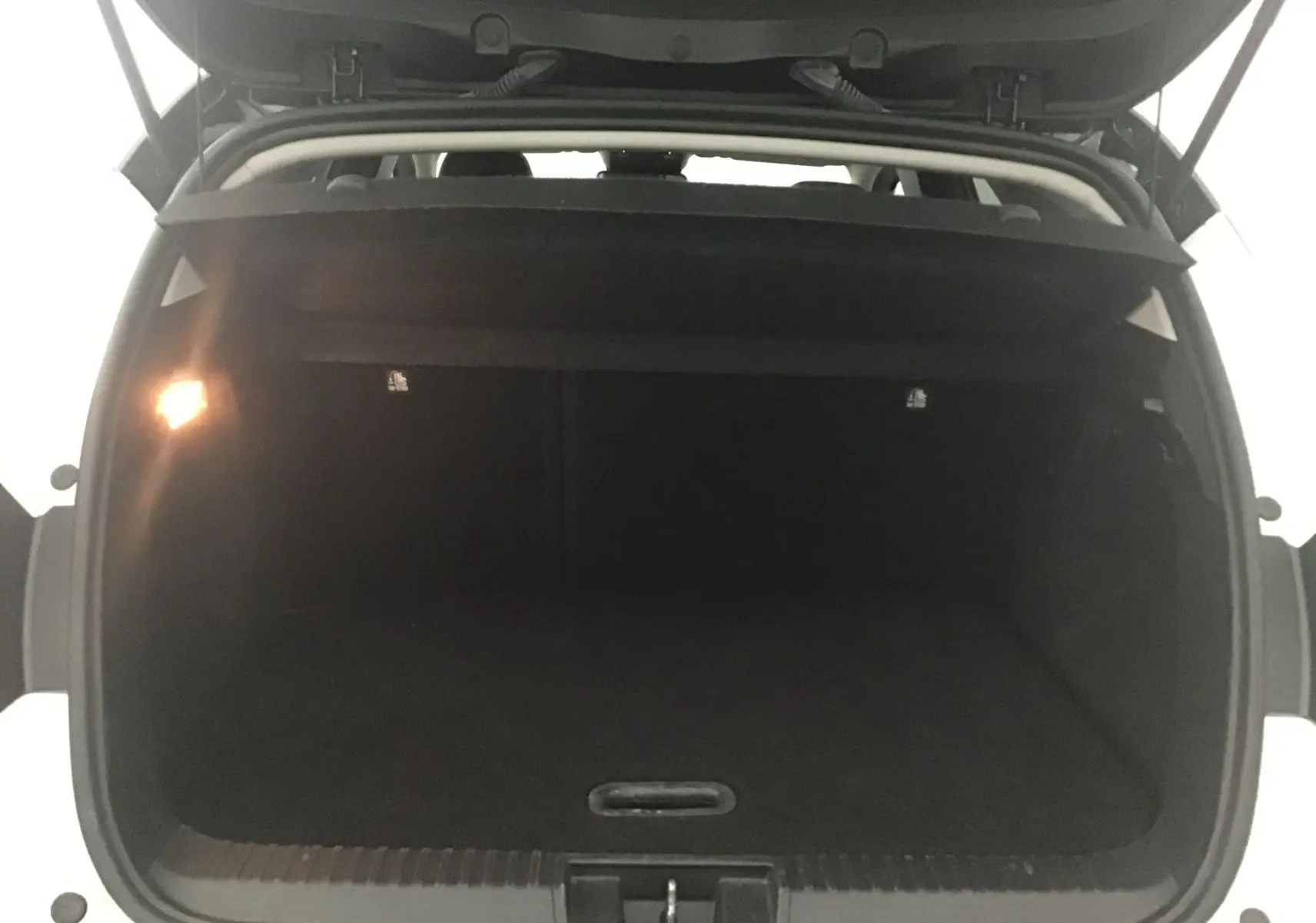 Coffre ouvert en vue arrière d'un Renault Captur blanc nacré/noir 2024, montrant l'espace de chargement vide et l'éclairage intérieur.