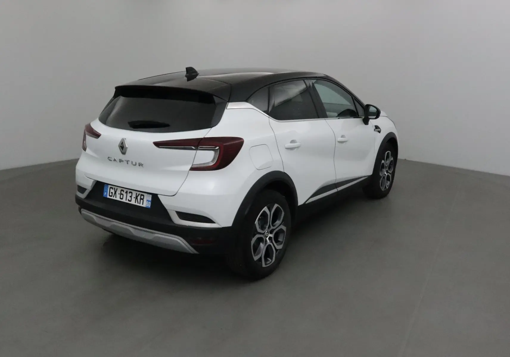 Renault Captur 2024 blanc nacré avec toit noir, vue 3/4 arrière droit mettant en valeur ses feux LED et jantes 18 pouces.