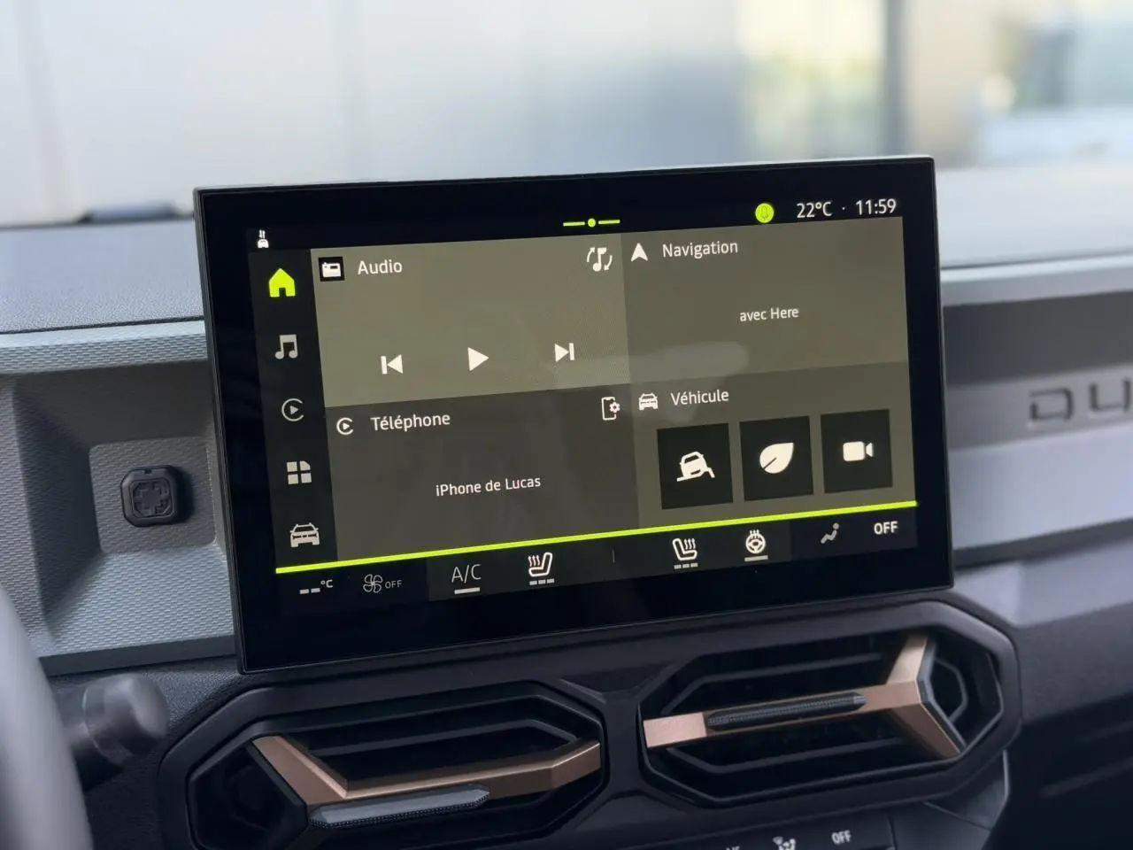 Écran tactile 10 pouces du tableau de bord du Dacia Duster 2025, avec commandes climatisation et finition brun cuivré.