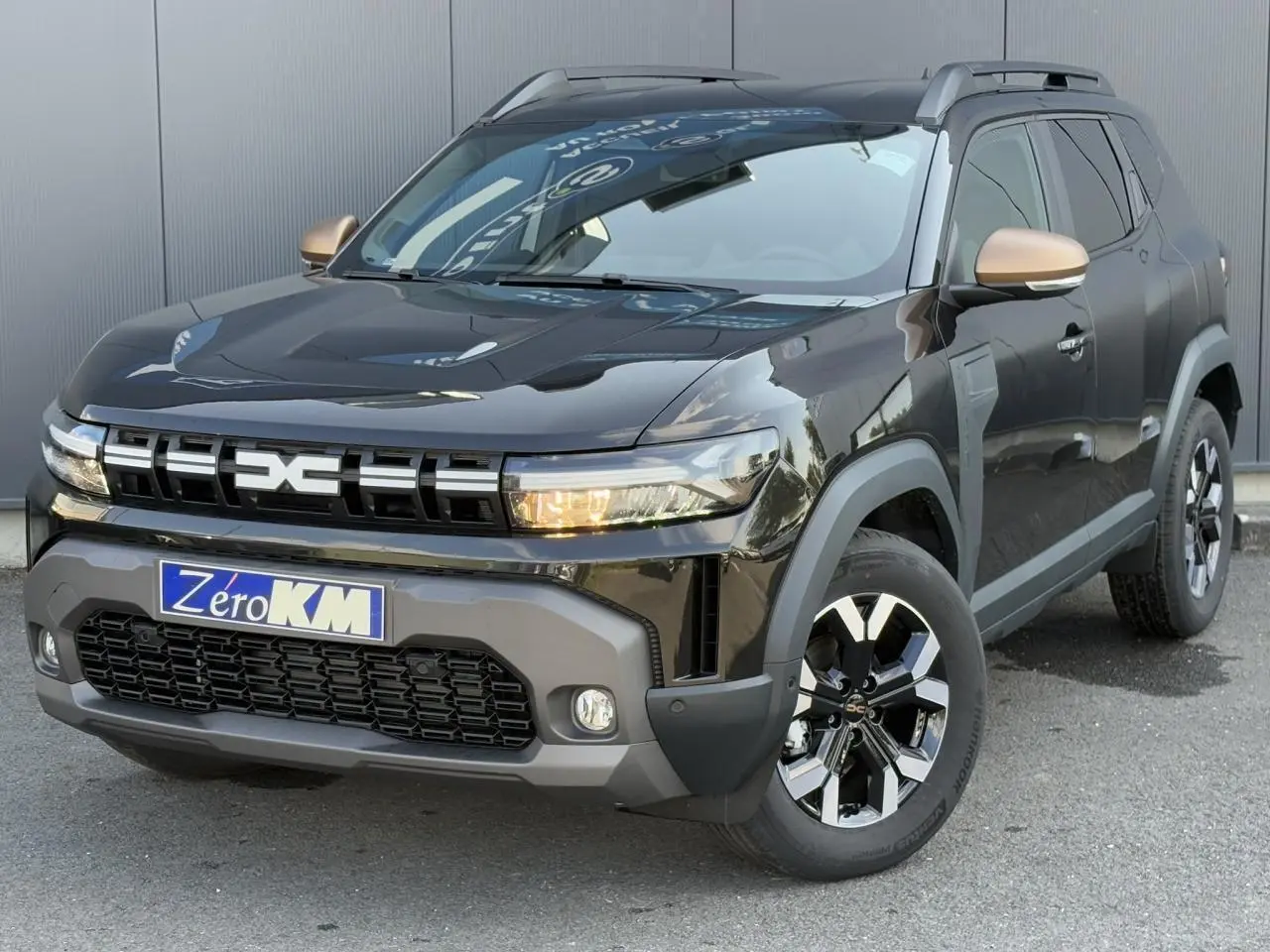 Vue 3/4 avant droite du Dacia Duster 2025 noir nacré avec coques de rétroviseur brun cuivré et jantes alliage 17 pouces.