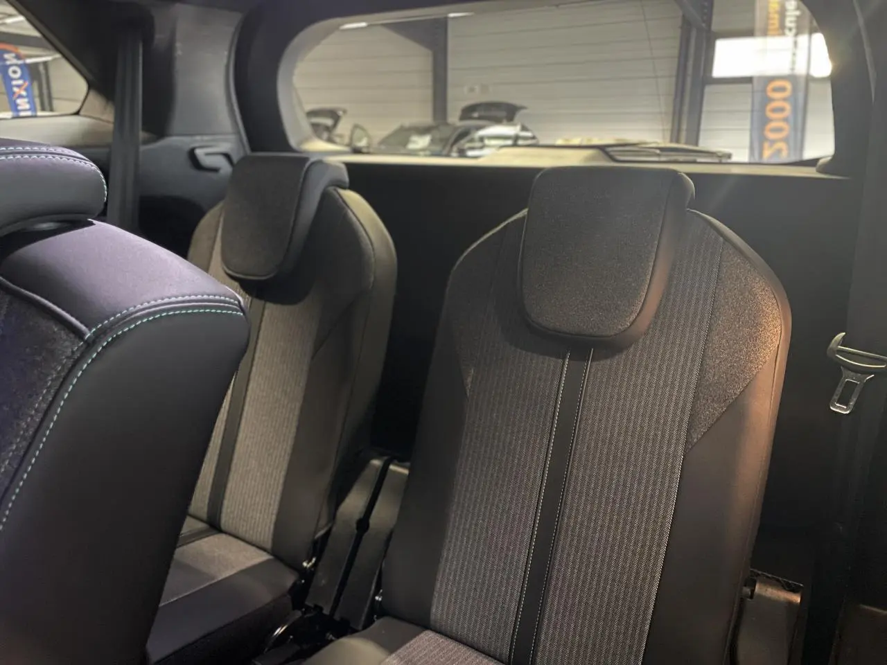 Sièges arrière indépendants noirs et gris du Peugeot 5008 2024 vus de côté droit dans un intérieur sombre