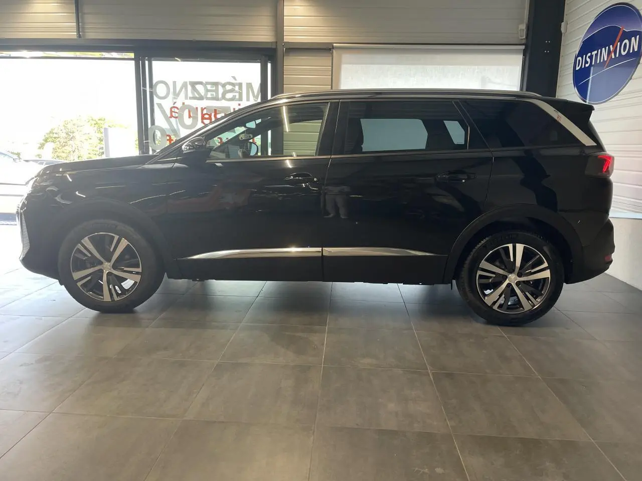 Peugeot 5008 noir métallisé vue de profil côté gauche, avec jantes alliage bi-ton et barres de toit profilées.