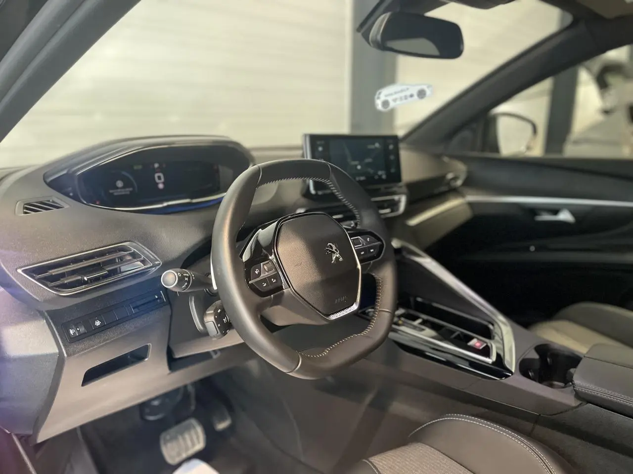 Intérieur du Peugeot 5008 2024 vu côté conducteur, volant compact et tableau de bord numérique avec écran tactile central.