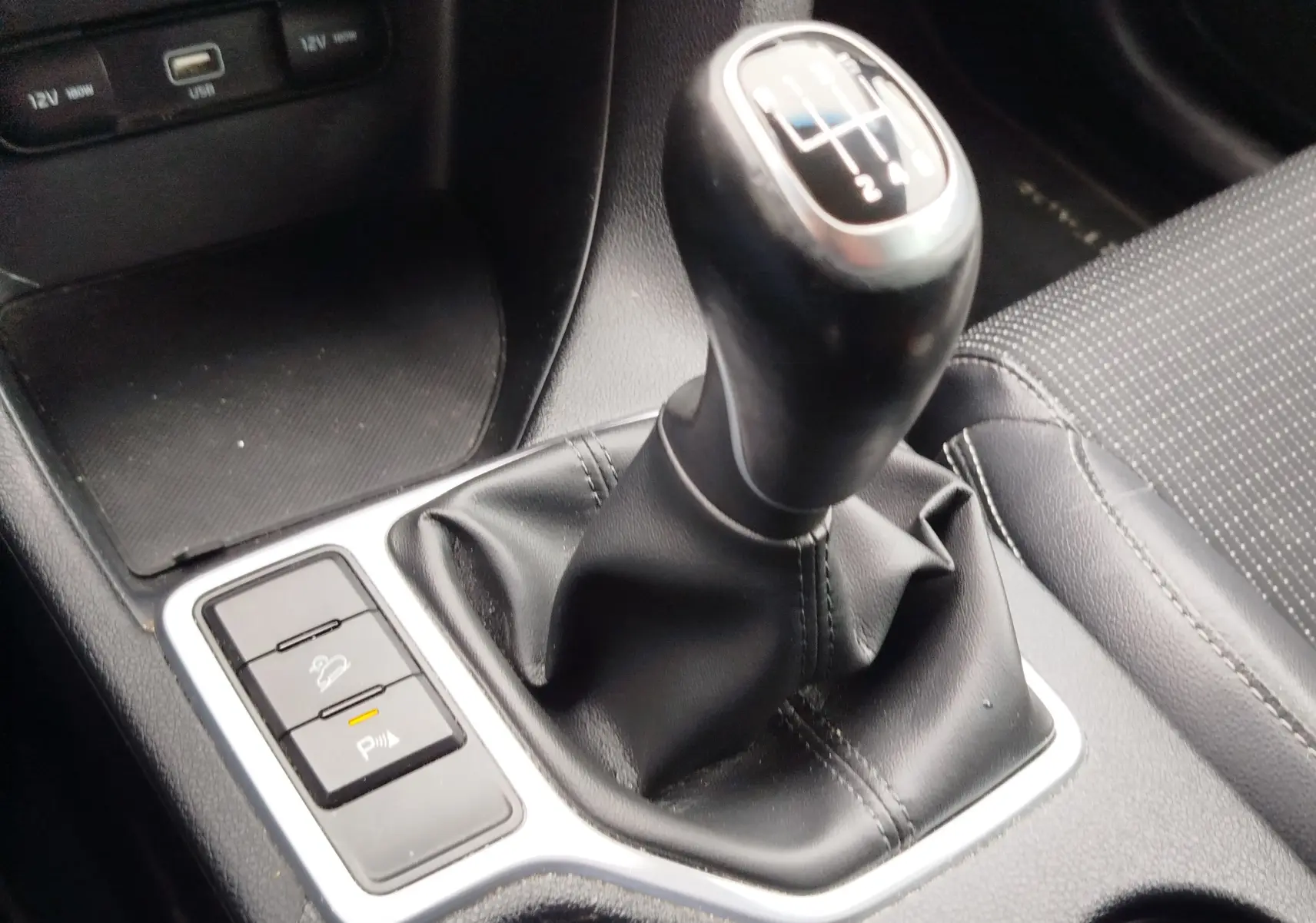 Gros plan sur le levier de vitesses manuel noir et les boutons de contrôle du Kia Sportage blanc 2022.