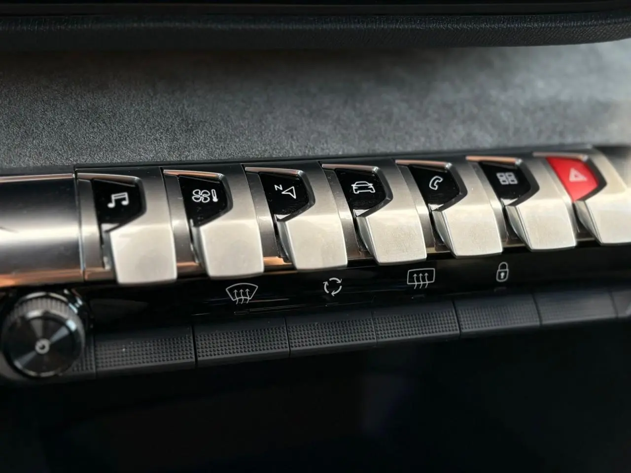 Gros plan sur les commandes en métal brossé du tableau de bord du Peugeot 3008 GT 2023, avec touches fonctionnelles noires.
