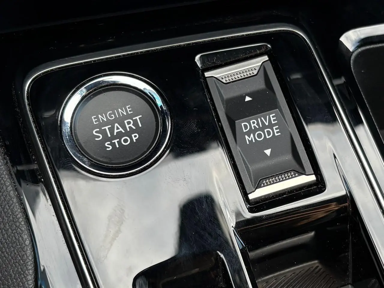 Gros plan sur la console centrale noire brillante du Peugeot 3008 2023, avec bouton Start/Stop et commande Drive Mode.