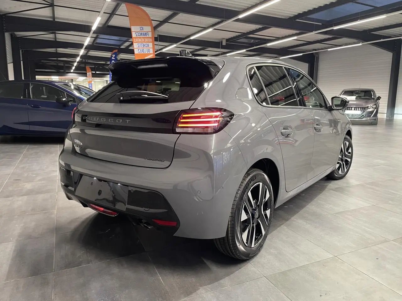 Vue 3/4 arrière droite d'une Peugeot 208 hybride gris selenium avec feux arrière à signature LED et jantes alliage bi-ton.