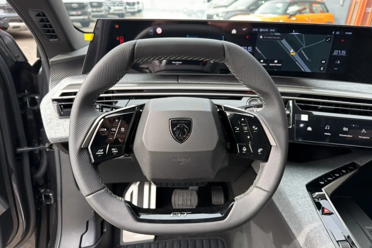 Vue rapprochée du volant cuir gris avec logo Peugeot et tableau de bord numérique du 3008 Hybrid 145 GT Alcantara.