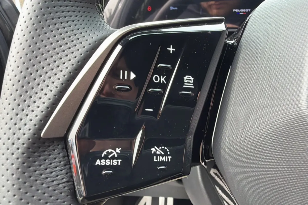 Gros plan sur les commandes multifonctions du volant cuir perforé du Peugeot 3008 Hybrid gris titane.