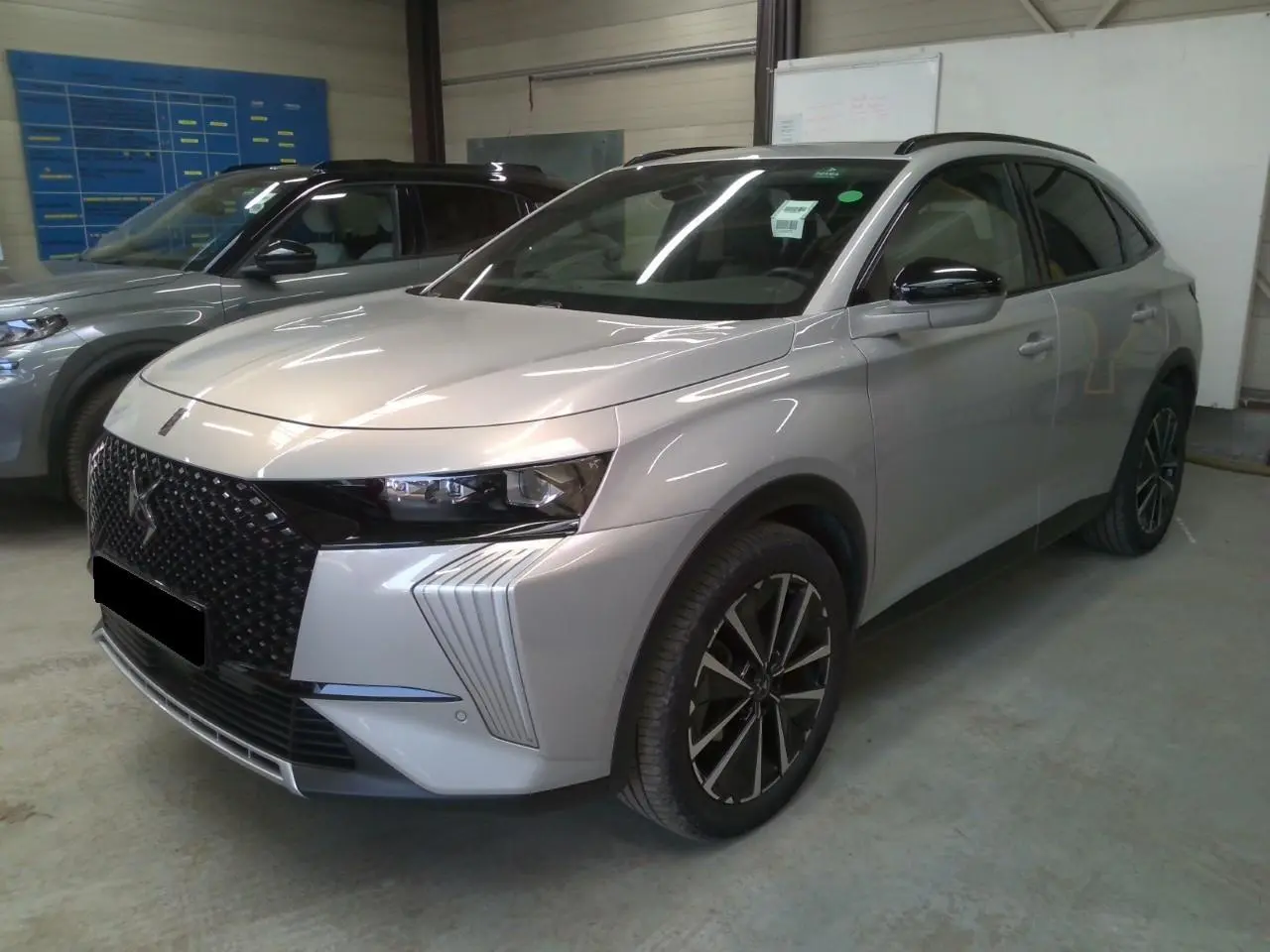 DS7 2025 Cristal Pearl en 3/4 avant droit, avec calandre noire distinctive et jantes alliage noires.