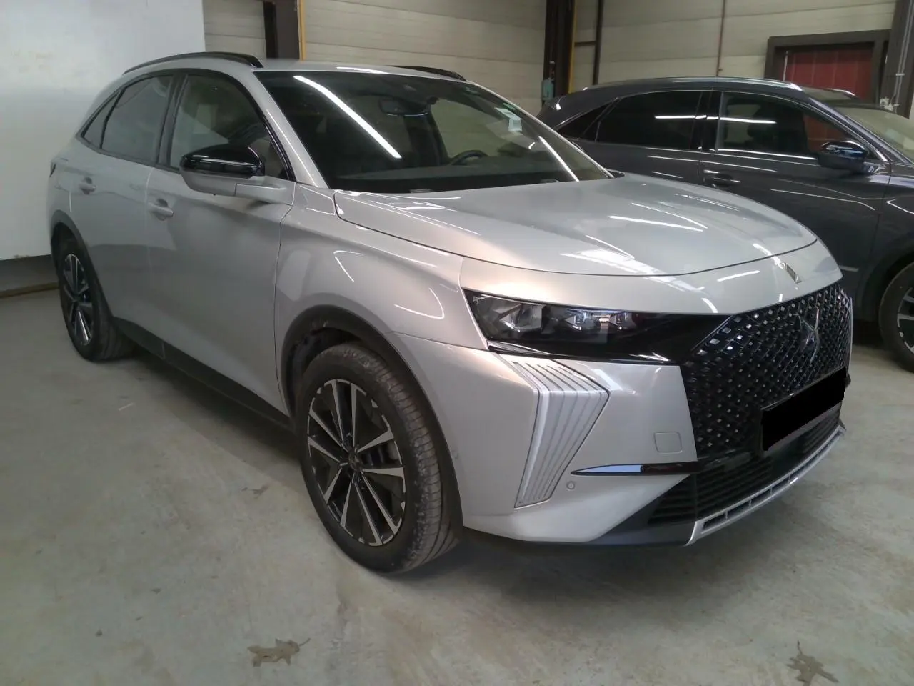 DS7 2025 Cristal Pearl en 3/4 avant droit, avec calandre noire distinctive et jantes alliage 19 pouces.