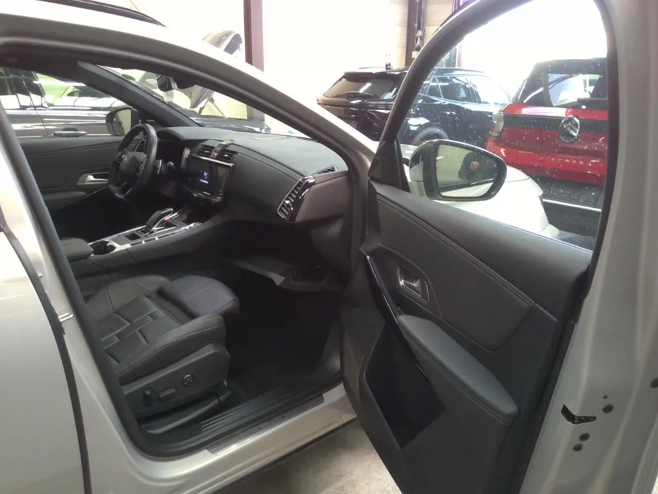 Vue intérieure côté conducteur du DS7 Cristal Pearl 2025, mettant en valeur la sellerie cuir noir et la console centrale moderne.