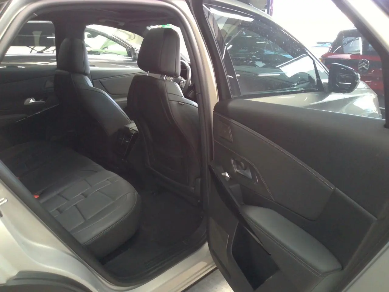 Vue intérieure côté arrière gauche du DS7 Cristal Pearl, montrant la porte ouverte et les sièges en cuir noir.