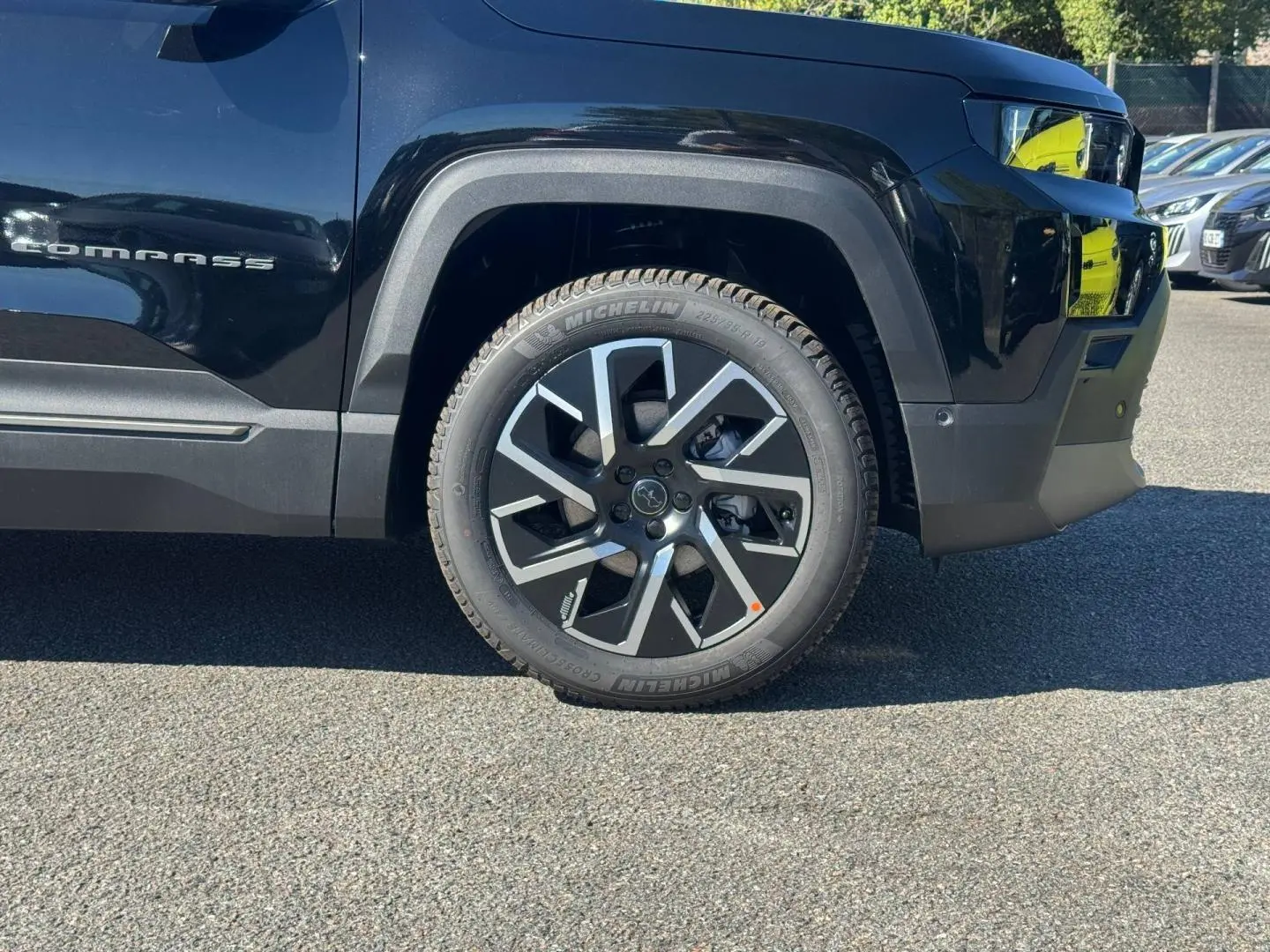 Gros plan sur la roue avant droite et la partie latérale noire du Jeep Compass 2026 avec jante alu distinctive.