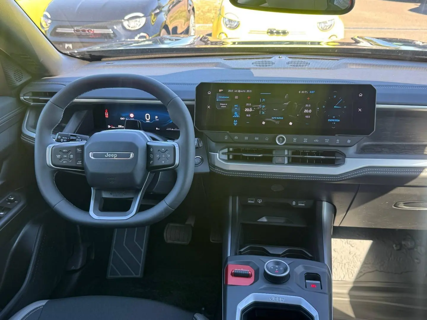 Vue intérieure frontale du tableau de bord et volant Jeep Compass 2026 avec écran tactile large et commandes au volant.