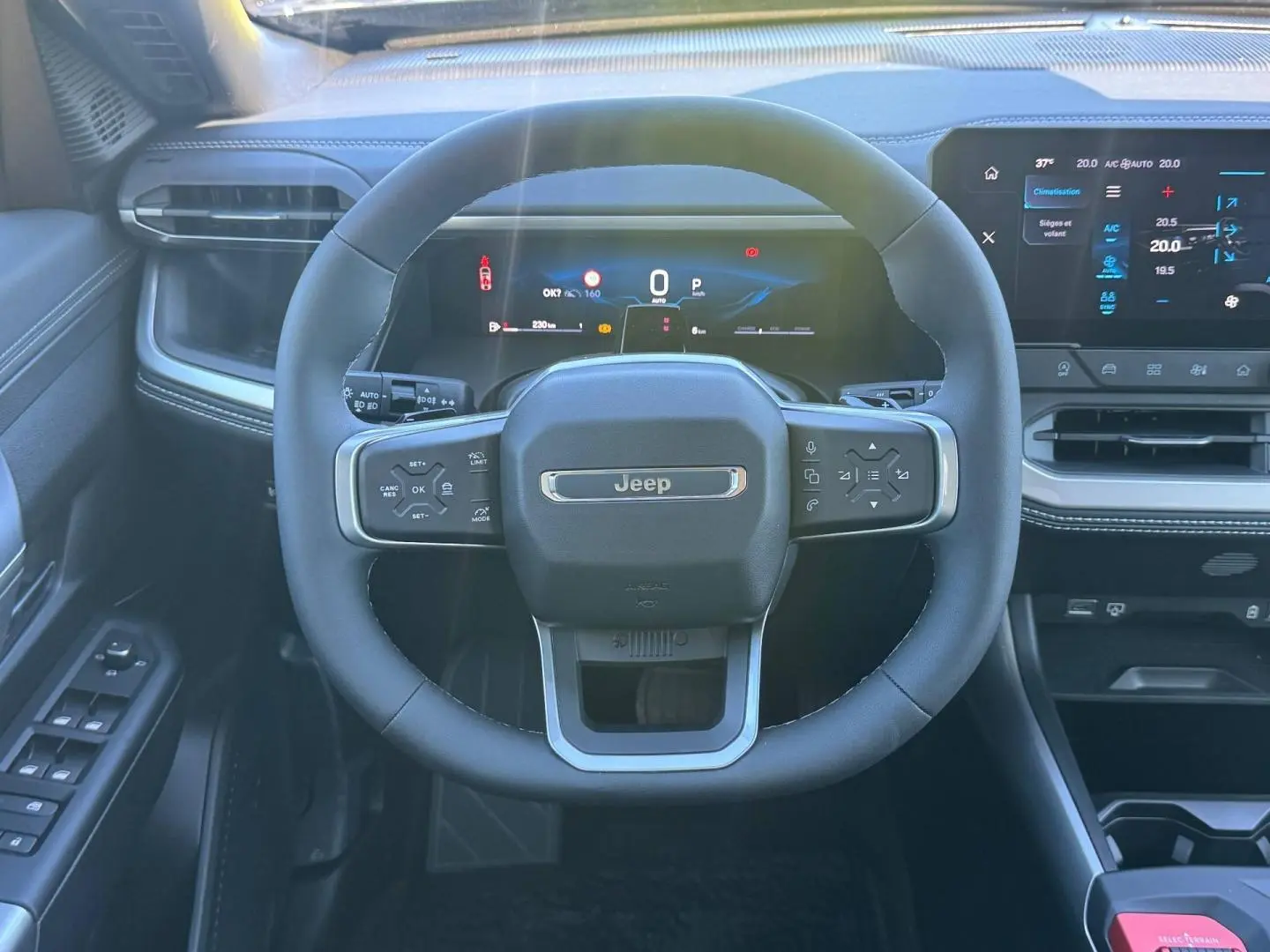 Vue intérieure centrée sur le volant Jeep du Compass 2026, avec tableau de bord numérique et écran tactile à droite.